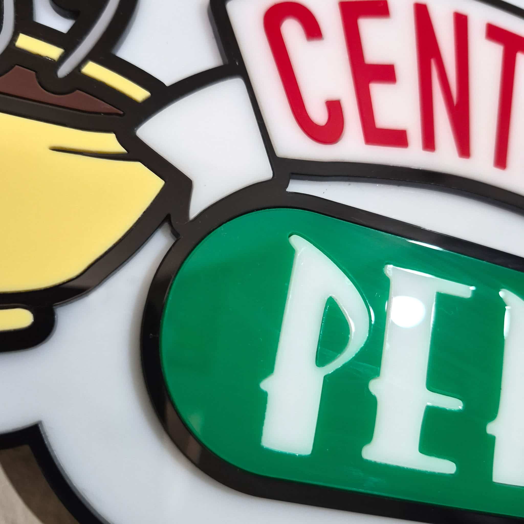 Close-up macro detail of a 3D acrylic Central Perk sign showing the raised white steam, yellow coffee cups, and seamless red and white flush-inlaid text.